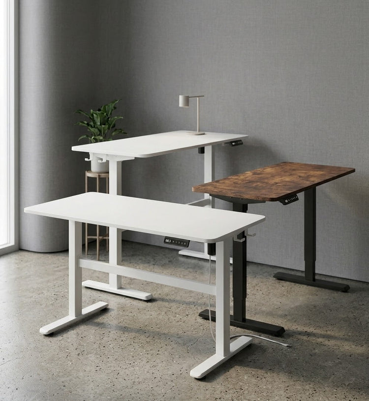 Three Kinetic height-adjustable desks side by side, two white and one rustic brown, shown at sitting and standing heights.